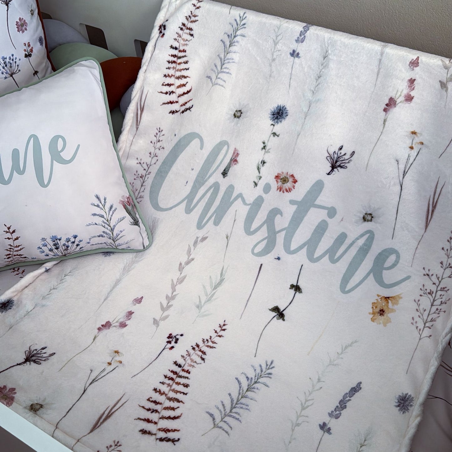 Floral-patterned blanket with 'Christine' printed on it, accompanied by a matching pillow.
