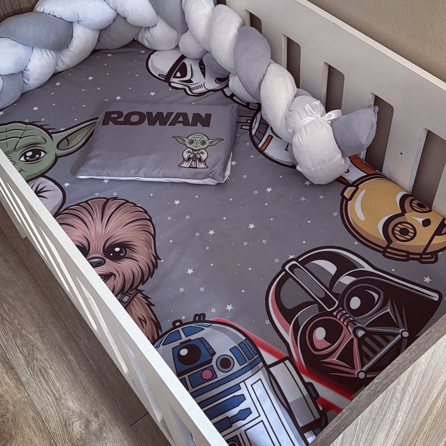 Children's crib with Star Wars-themed bedding featuring characters like Yoda, Chewbacca, R2-D2, and Darth Vader.