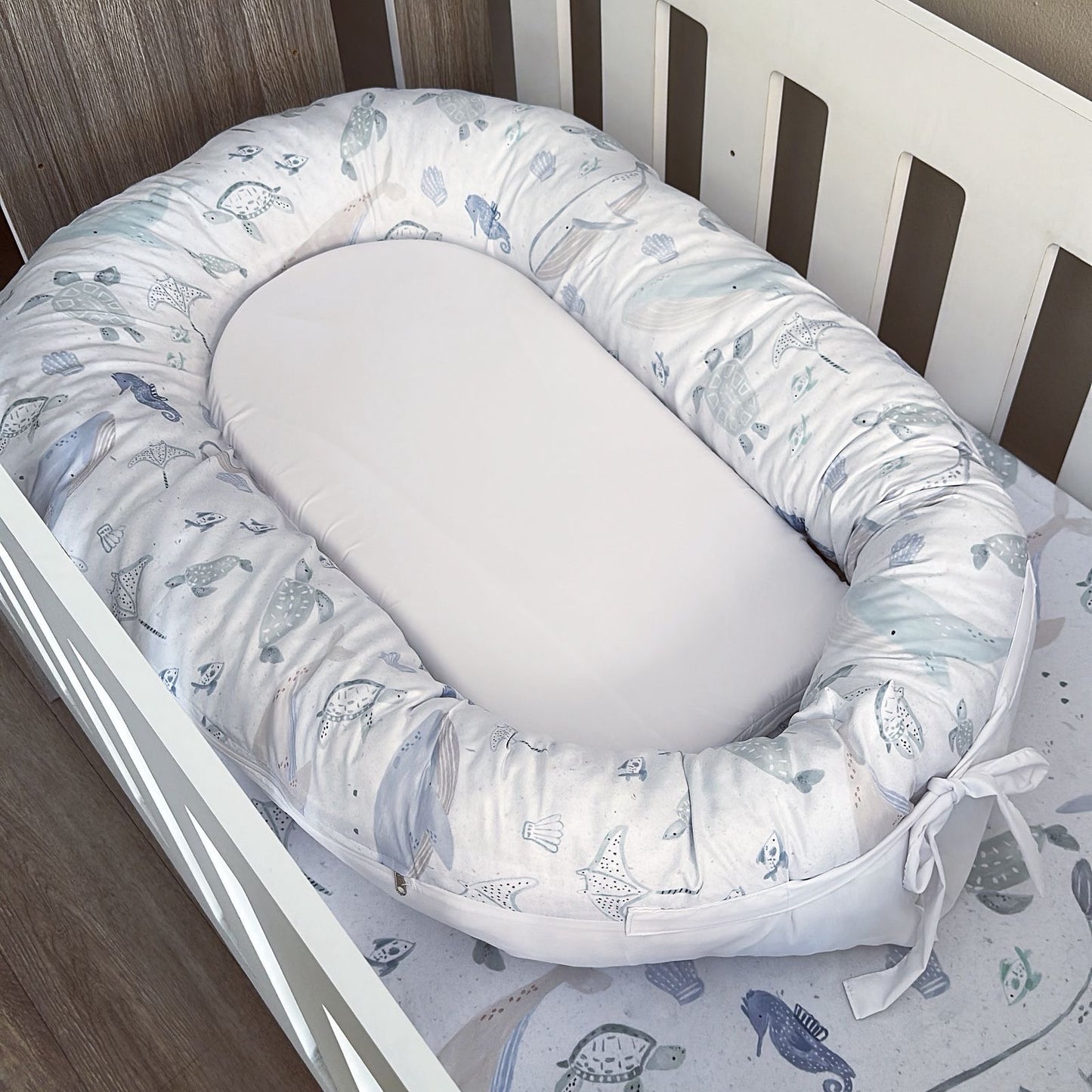 Baby nest with sea-themed print on a crib