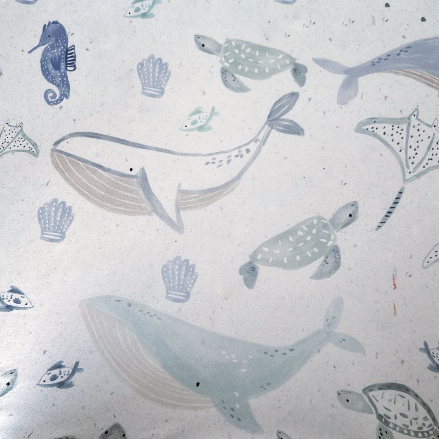 Pattern of whales, turtles, and seahorses on a textured white background