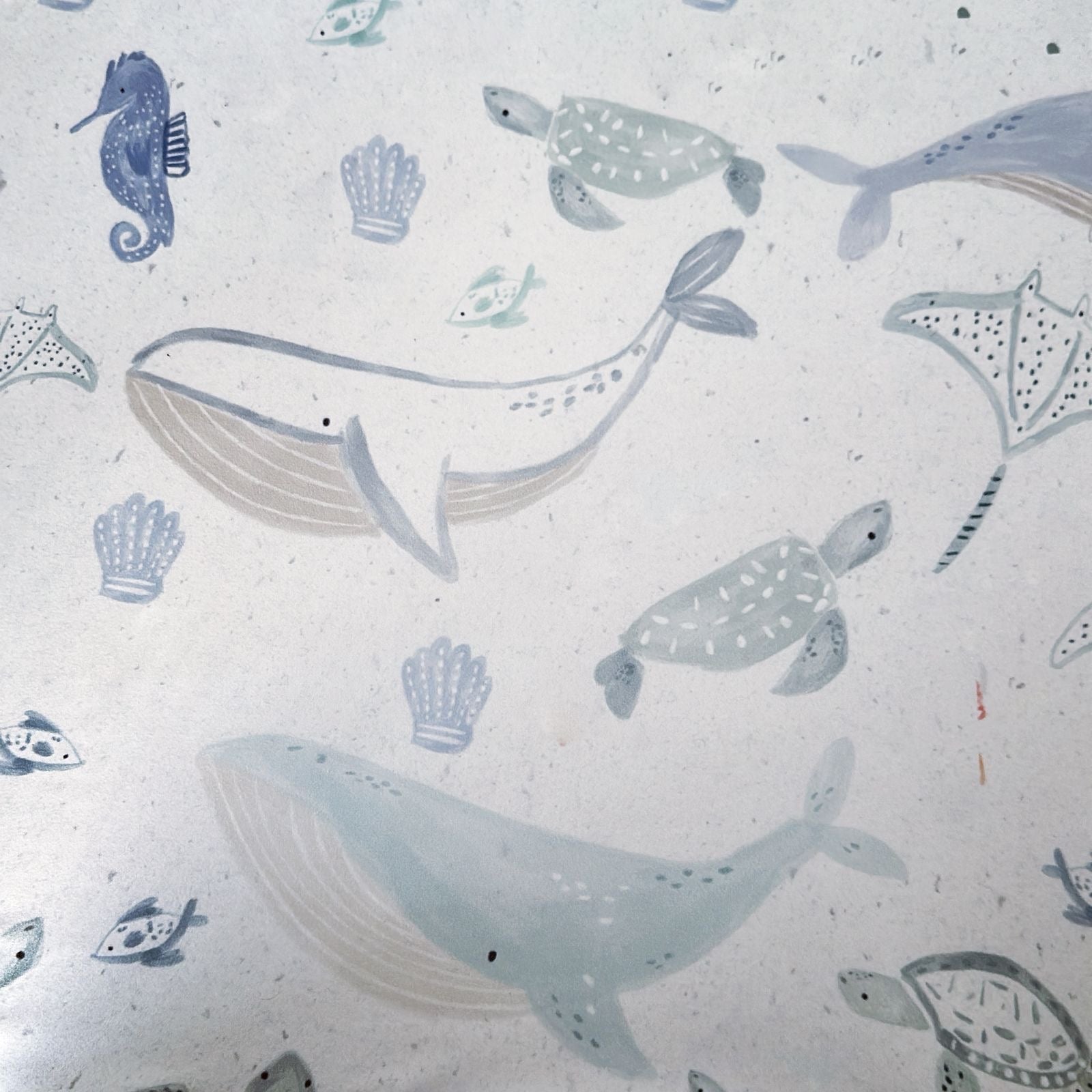 Pattern of whales, turtles, and seahorses on a textured white background