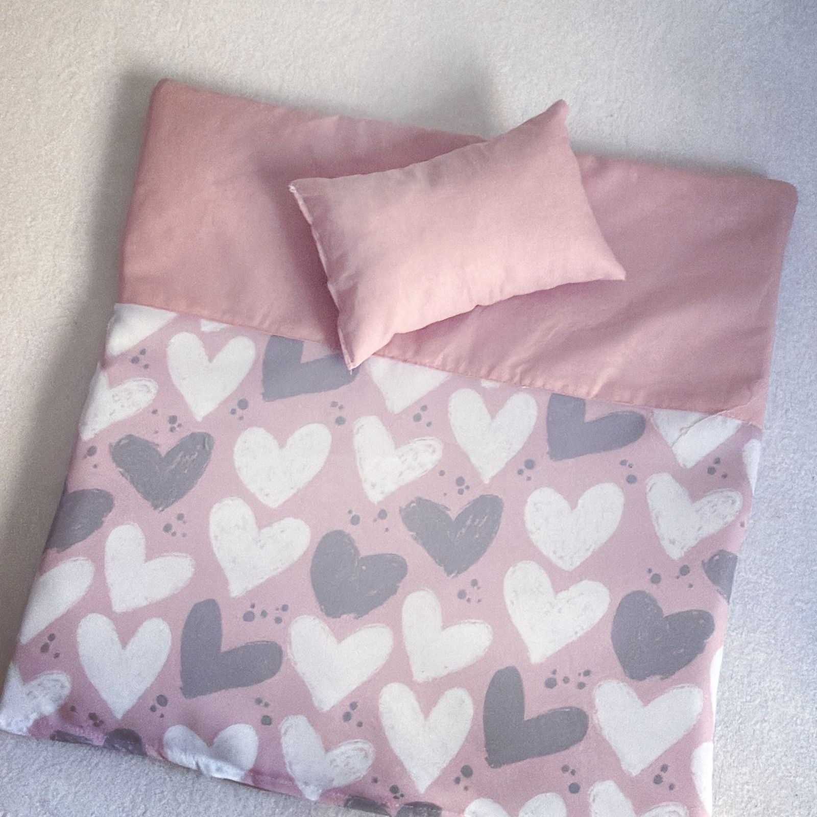 Pink bedspread with heart pattern and matching pillow on a light background