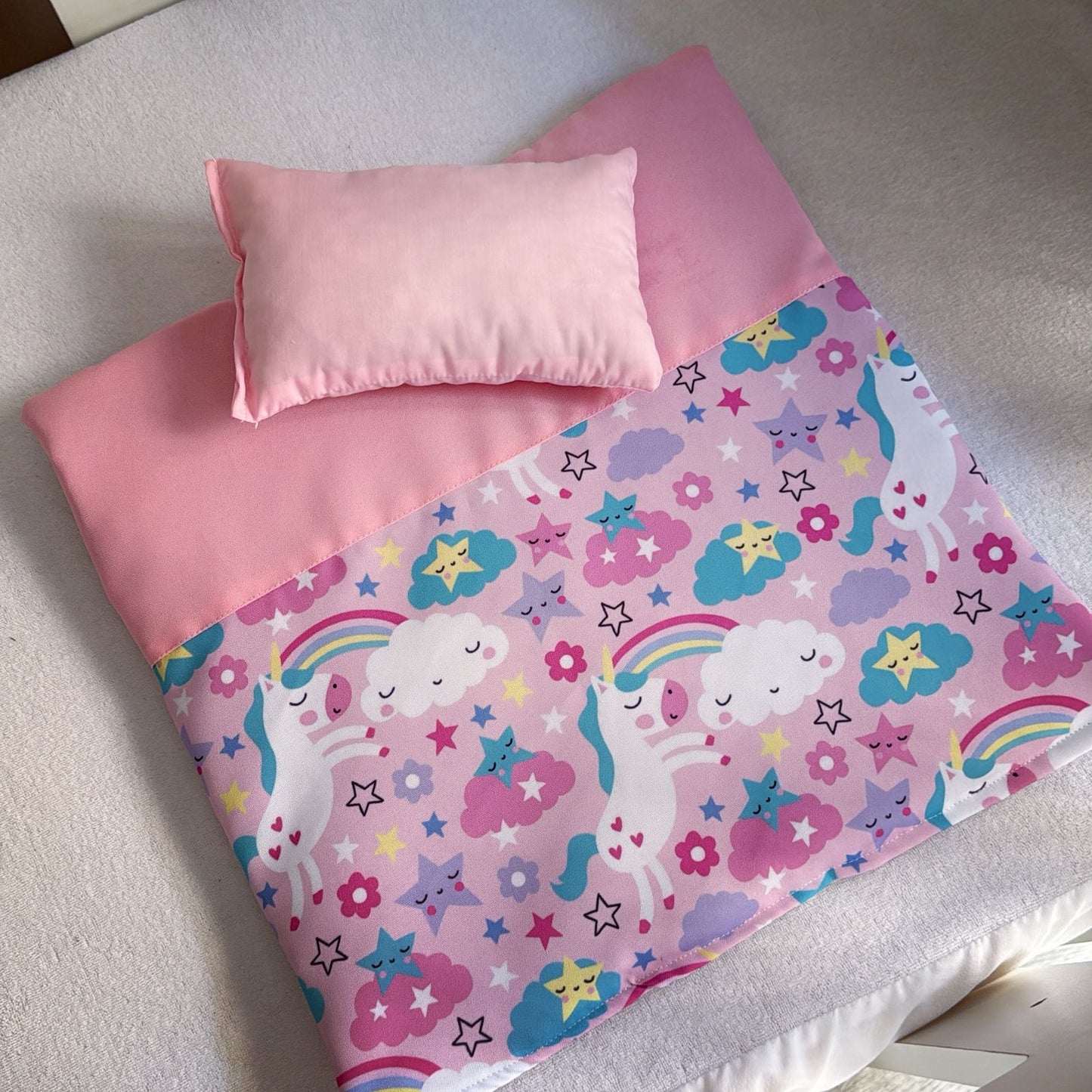 Children's bedspread with unicorn and rainbow pattern on a bed.