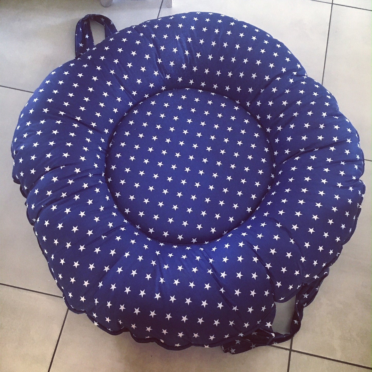 Blue cushion with white star pattern on a tiled floor