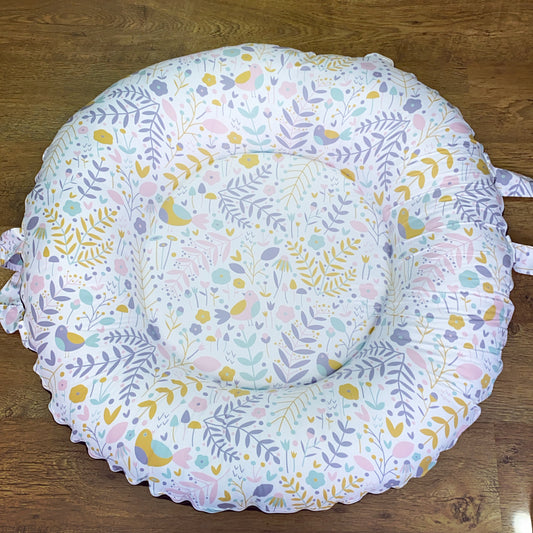 Round baby play mat with floral and bird pattern on a wooden floor