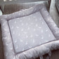 A padded baby mattress pad with a matching padded border, featuring a light gray center printed with a repeating pattern of white geese with orange beaks and feet, shown on a wooden floor. | Baby Doughnut Cushions | Infant Support Pillows | Soft Spot Kids | South Africa