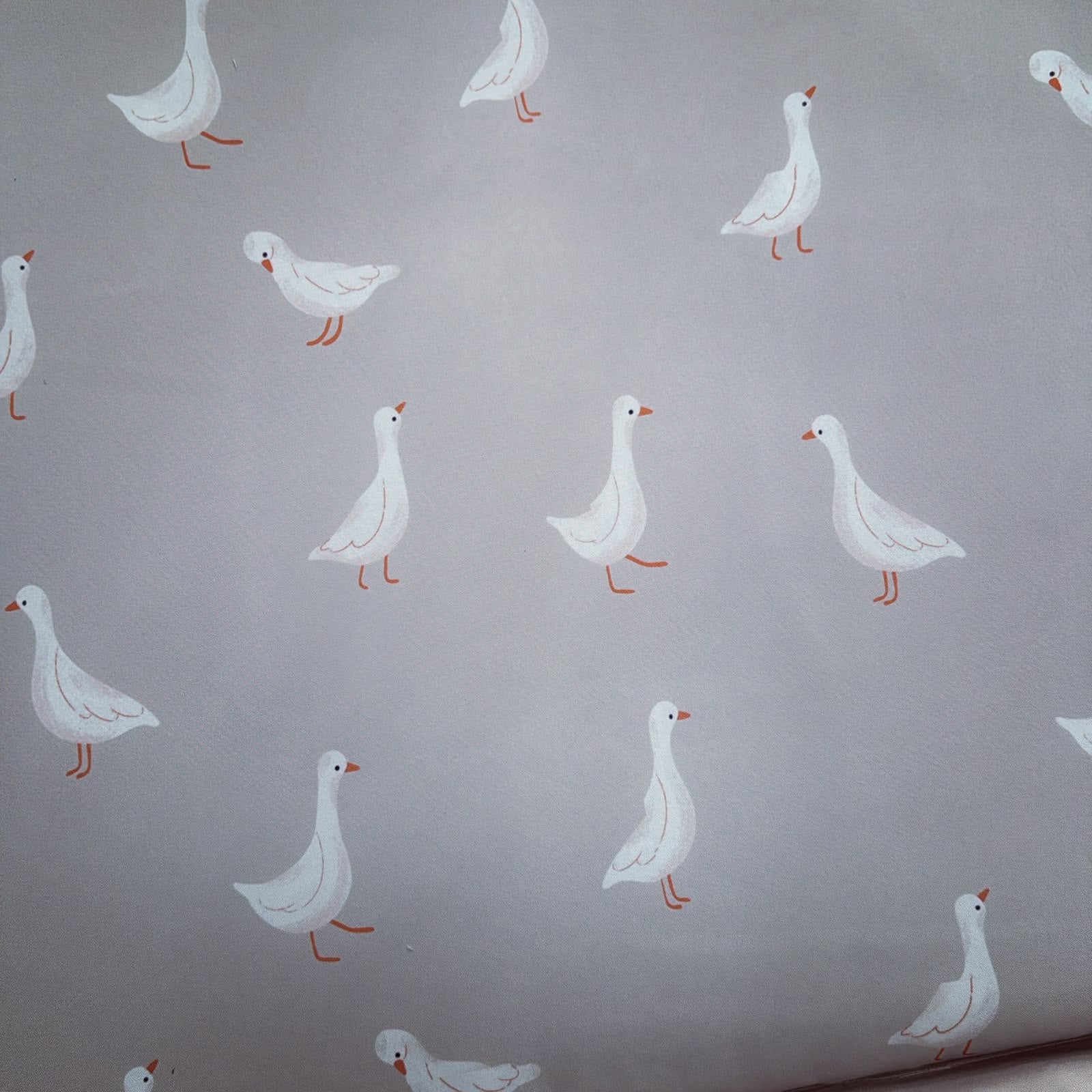 Light gray wallpaper featuring a repeating pattern of white geese with orange beaks and legs.