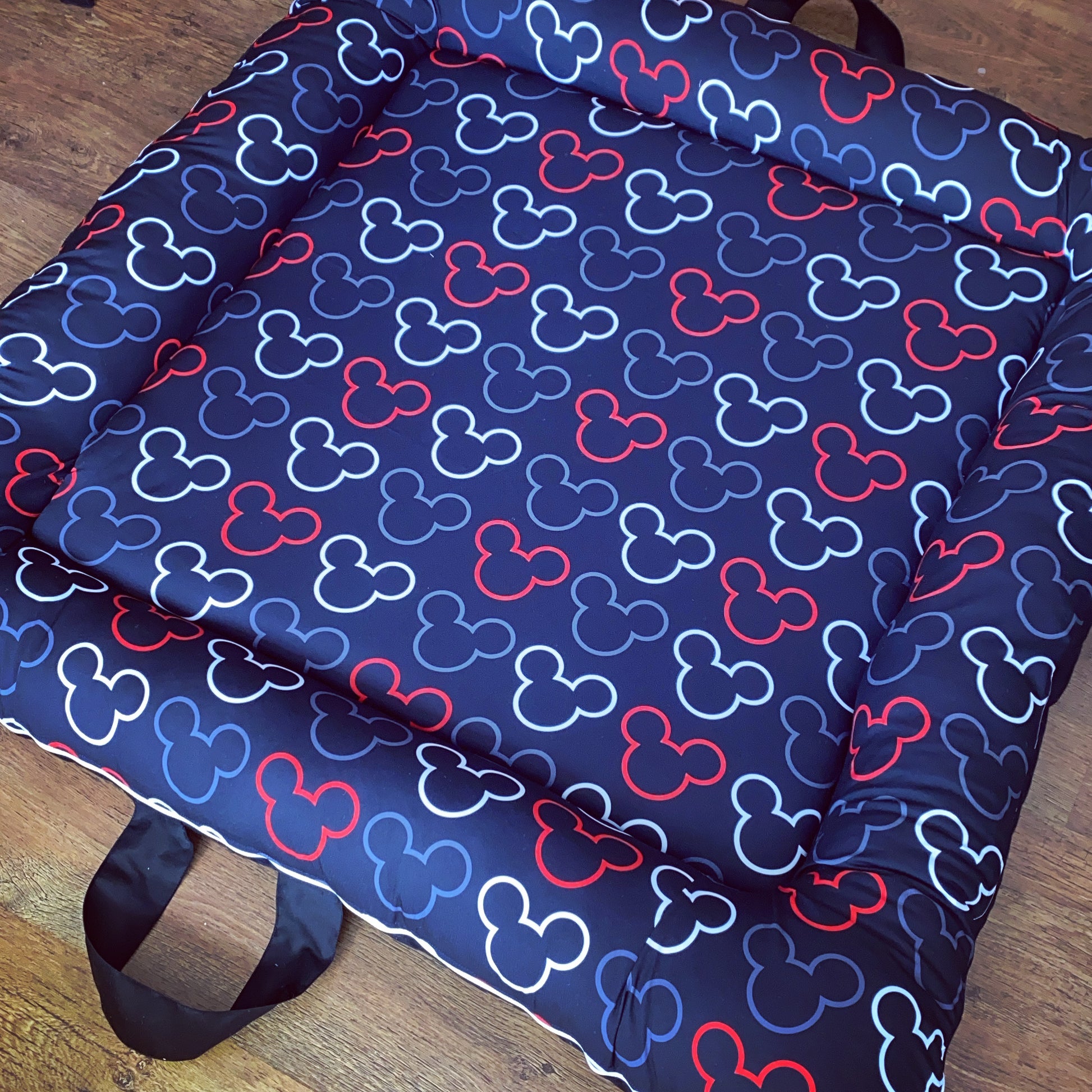 A soft play doughnut with a Mickey Mouse pattern in blue, red, and black, featuring a carry handle.