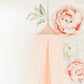 A pink hanging tent canopy with floral designs, set up in a room with a white background. It is positioned above a cream-colored feeding chair with a rose gold accent. | Baby Canopy Nets | Cot Mosquito Nets | Soft Spot Kids | South Africa