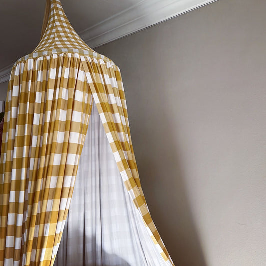 Yellow and white checkered curtain partially open on a gray wall.