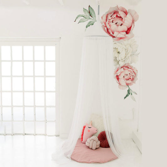 A white hanging tent canopy with a floral design, set up in a room with a window and a pink teddy bear underneath.