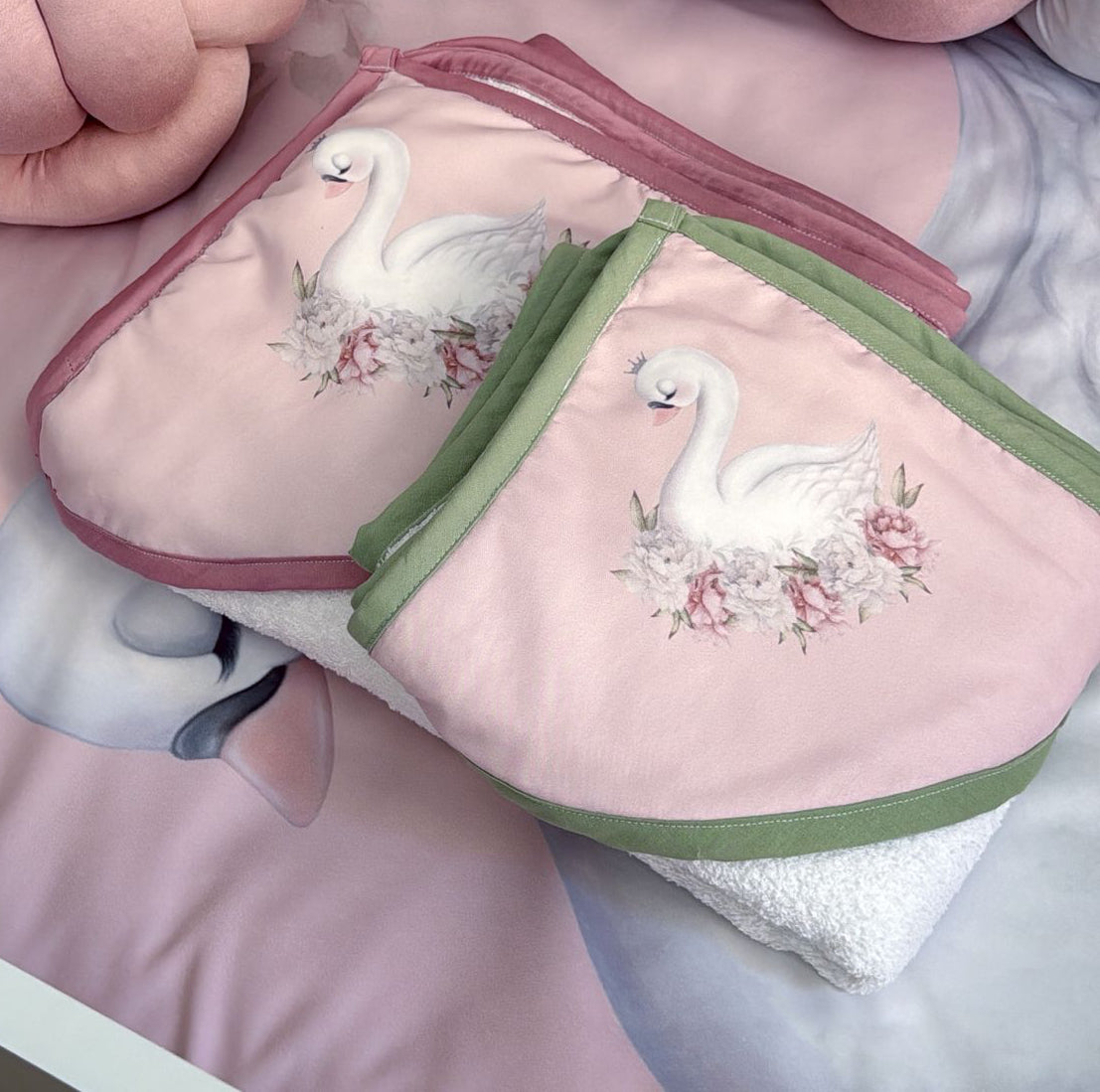 Pair of pink and green embroidered Hooded Towels - Swan 01 with swan design on a white surface.