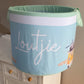 A large laundry basket with a green lid and white fabric, featuring the word 'LOUTJIE' in a large, cursive font, along with ocean-themed illustrations such as waves and seagulls. | Baby Essentials | All Baby Products | Soft Spot Kids | South Africa