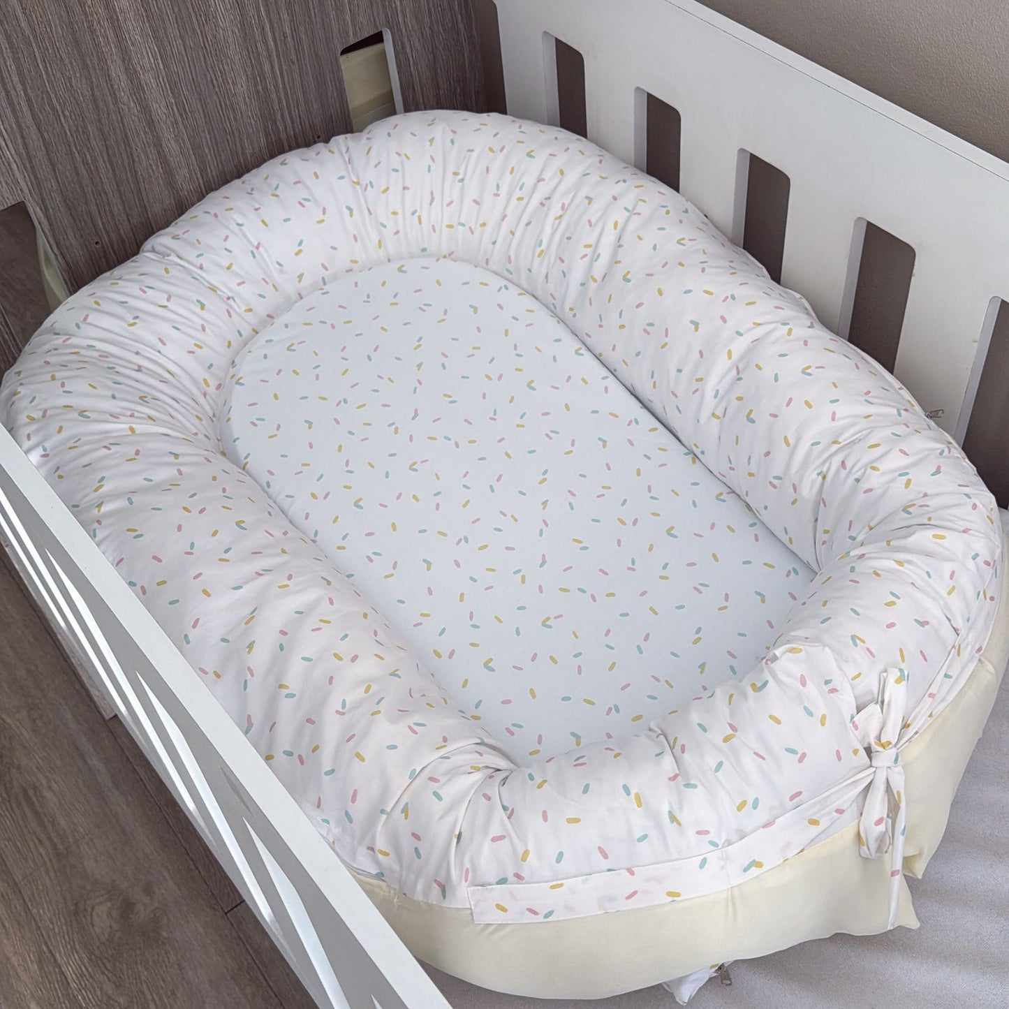 Baby nest with white and yellow pattern inside a crib