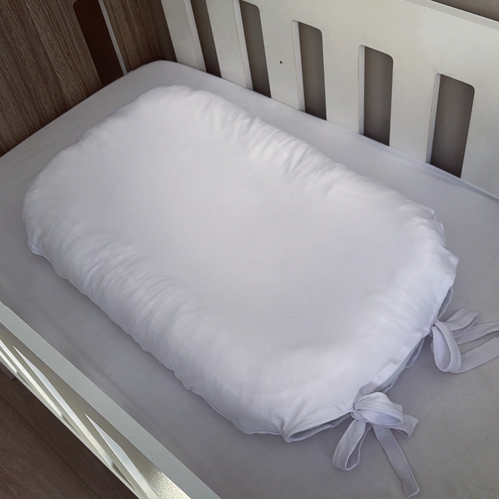 White crib bumper pad with ties on a crib