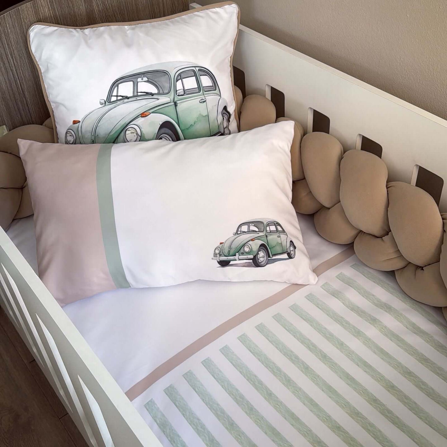 Children's room with crib and pillows featuring vintage car designs.