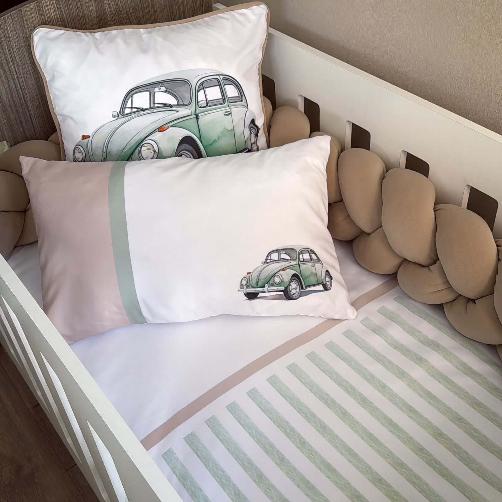 Children's room with crib and pillows featuring vintage car designs.