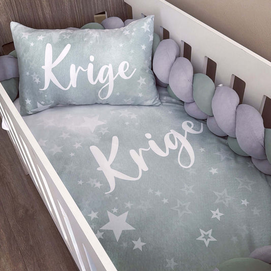 Crib with star-patterned bedding and 'Krige' pillow and sheet.