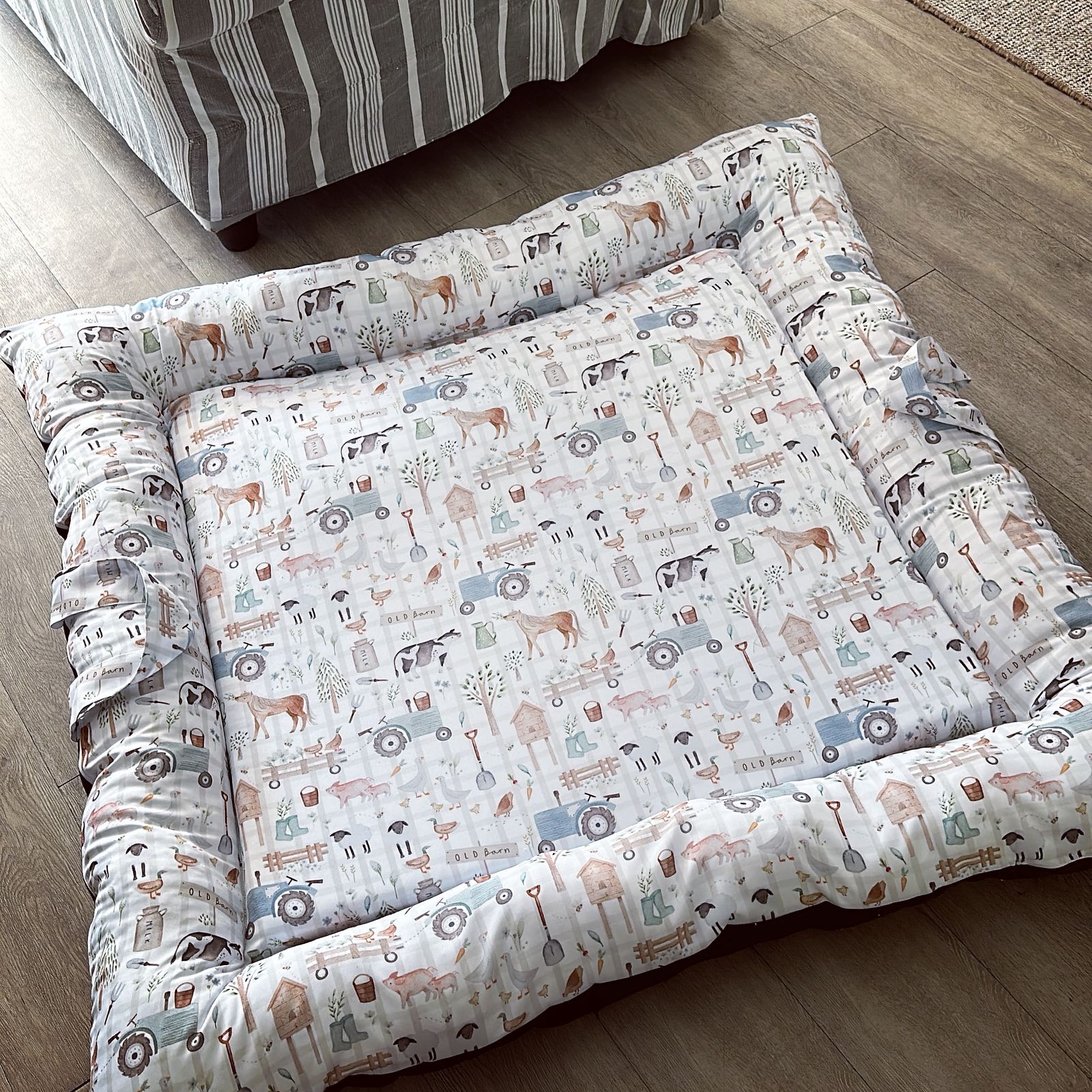 Patterned doughnut bed on a wooden floor with a striped rug in the background