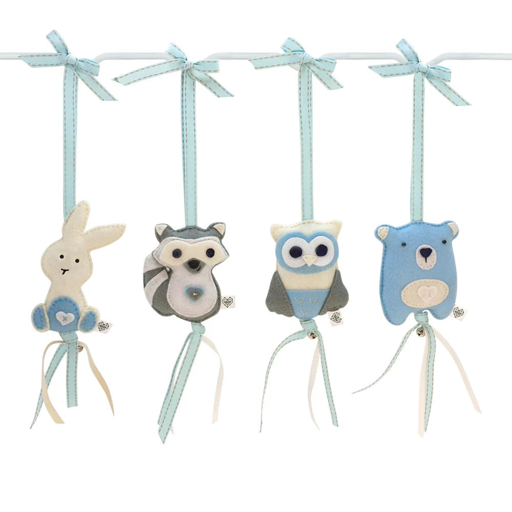 Four fabric animal hanging ornaments on a white bar with light blue ribbons: a bunny, raccoon, owl, and bear, shown on a plain white background.
