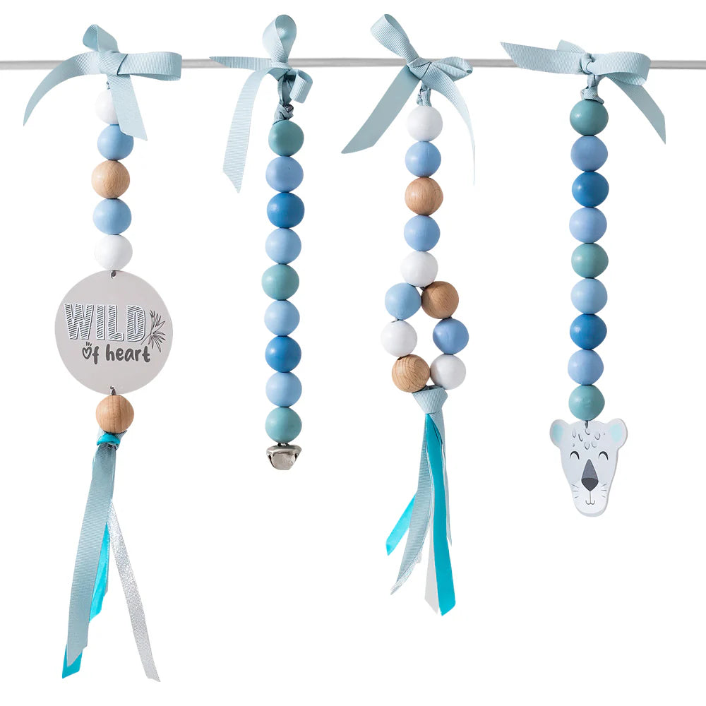 A set of four beaded baby teething rings hanging from a metal rod with light blue ribbons. The rings feature pastel blue, mint green, white, and natural wood beads, with one ring decorated with a round wooden disc that reads 'WILD heart' and another with a koala head charm.