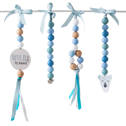 A set of four beaded baby teething rings hanging from a metal rod with light blue ribbons. The rings feature pastel blue, mint green, white, and natural wood beads, with one ring decorated with a round wooden disc that reads 'WILD heart' and another with a koala head charm.