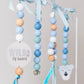 A hanging baby mobile or bead garland with pastel blue, white, and natural wood beads, light blue ribbons, a round white sign reading 'Wild of heart,' and a white polar bear face charm against a soft light gray background. | Baby Essentials | All Baby Products | Soft Spot Kids | South Africa