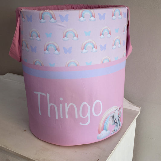 A pink laundry basket with a pattern of rainbows, clouds, and an elephant, and the word 'THINGO' printed on it.