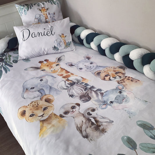 A toddler bedding set with a safari animals theme, including a duvet cover, pillowcases, and a fitted sheet, displayed on a bed with a child's name 'Daniel' on one of the pillowcases.