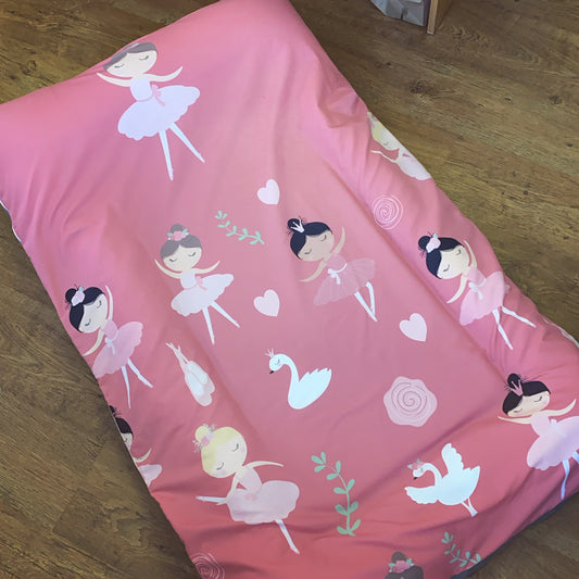 Pink blanket with ballerina and swan designs on a wooden floor
