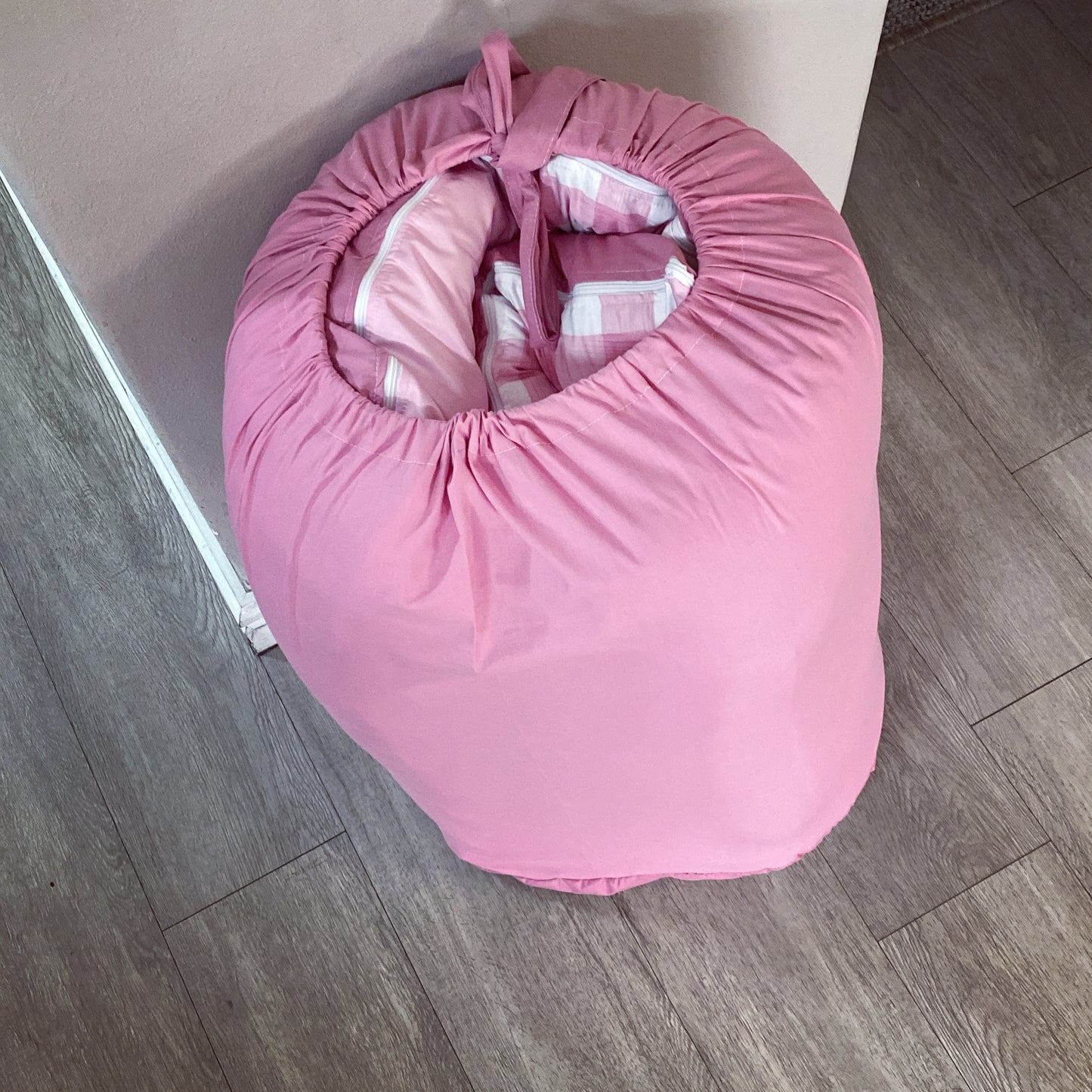 Pink baby seat cover on a wooden floor