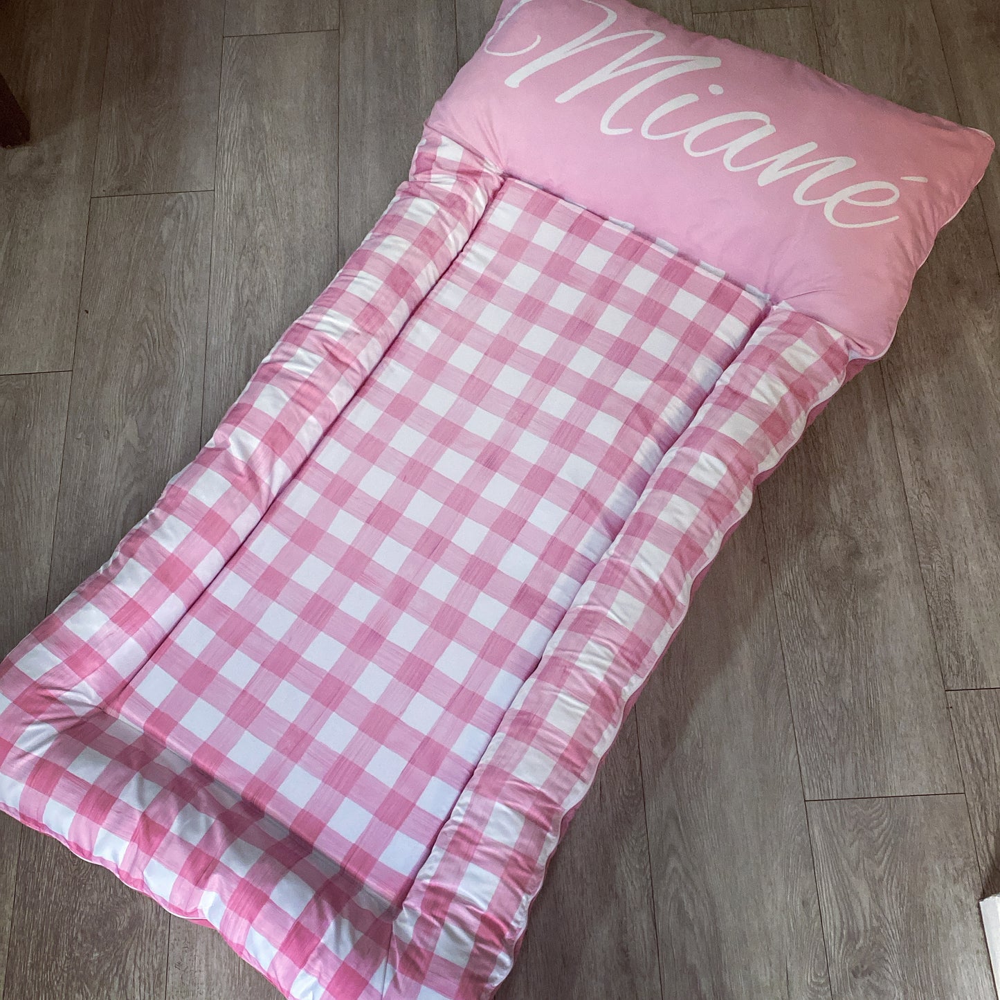 Pink checkered baby wrap with 'Miaane' branding on a wooden floor