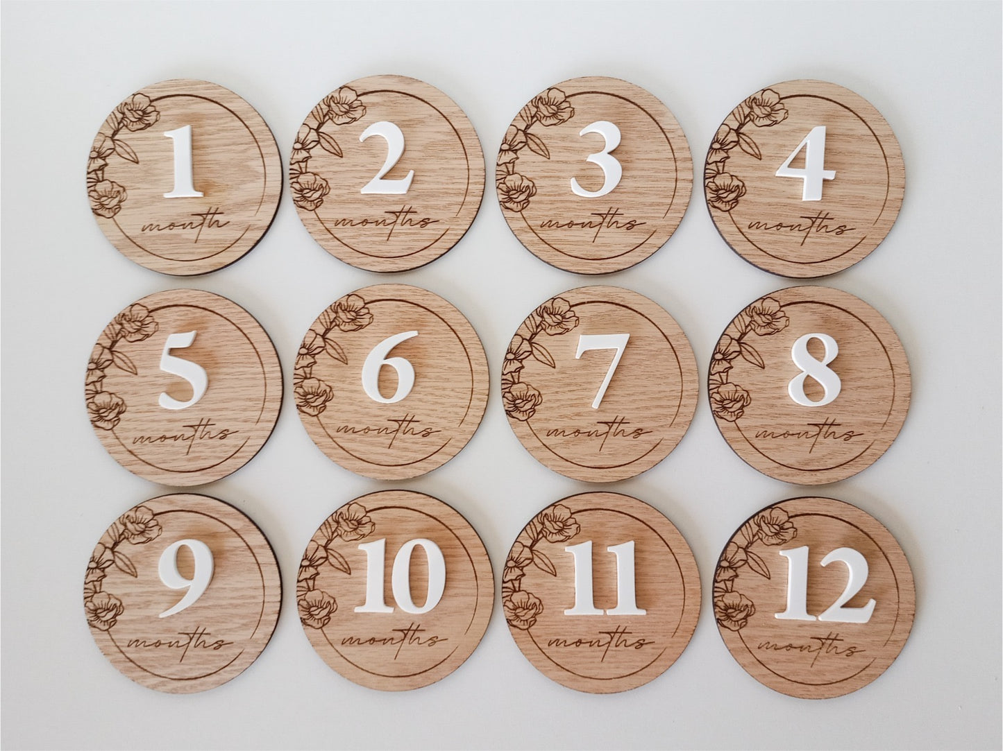 Wooden milestone discs with numbers 1 to 12 months on a white background