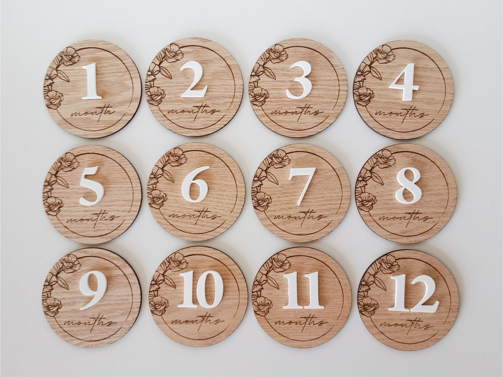 Wooden milestone discs with numbers 1 to 12 months on a white background