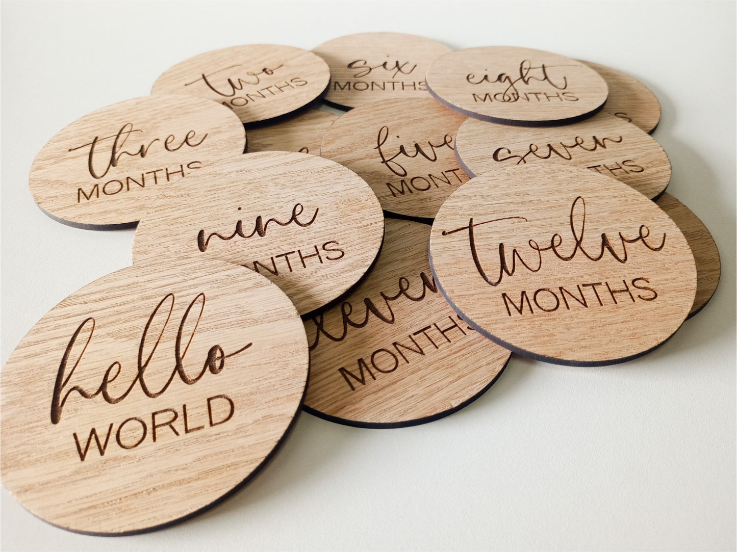 Wooden discs with milestone text for baby's first year on a white background