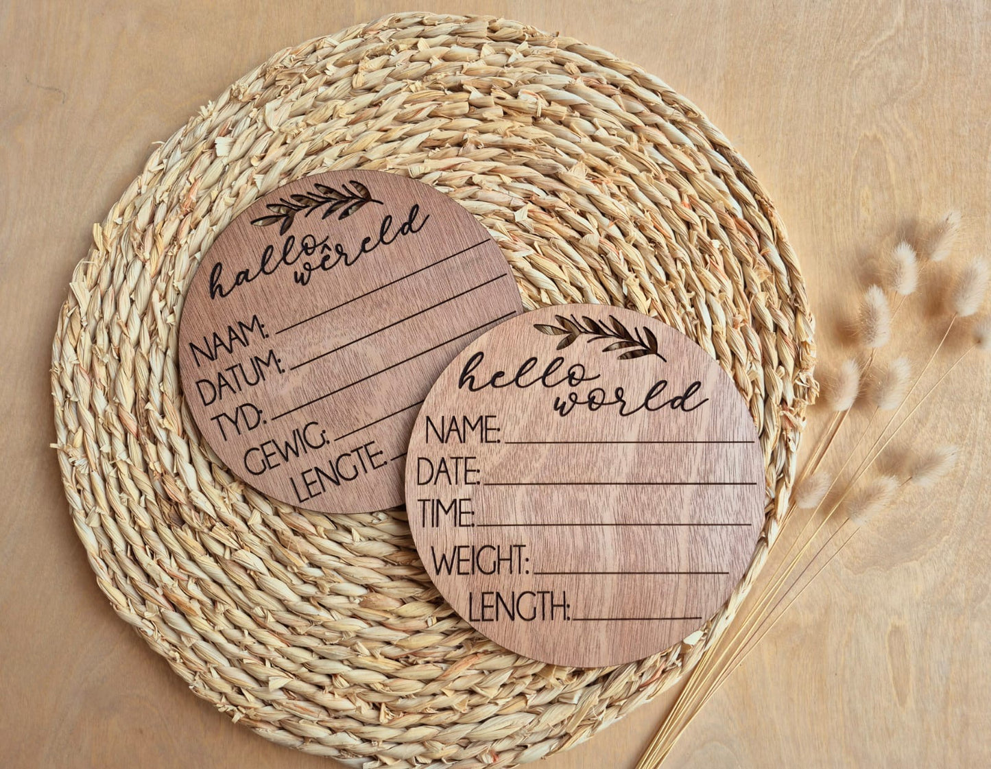 Two wooden baby announcement cards with text on a woven mat.