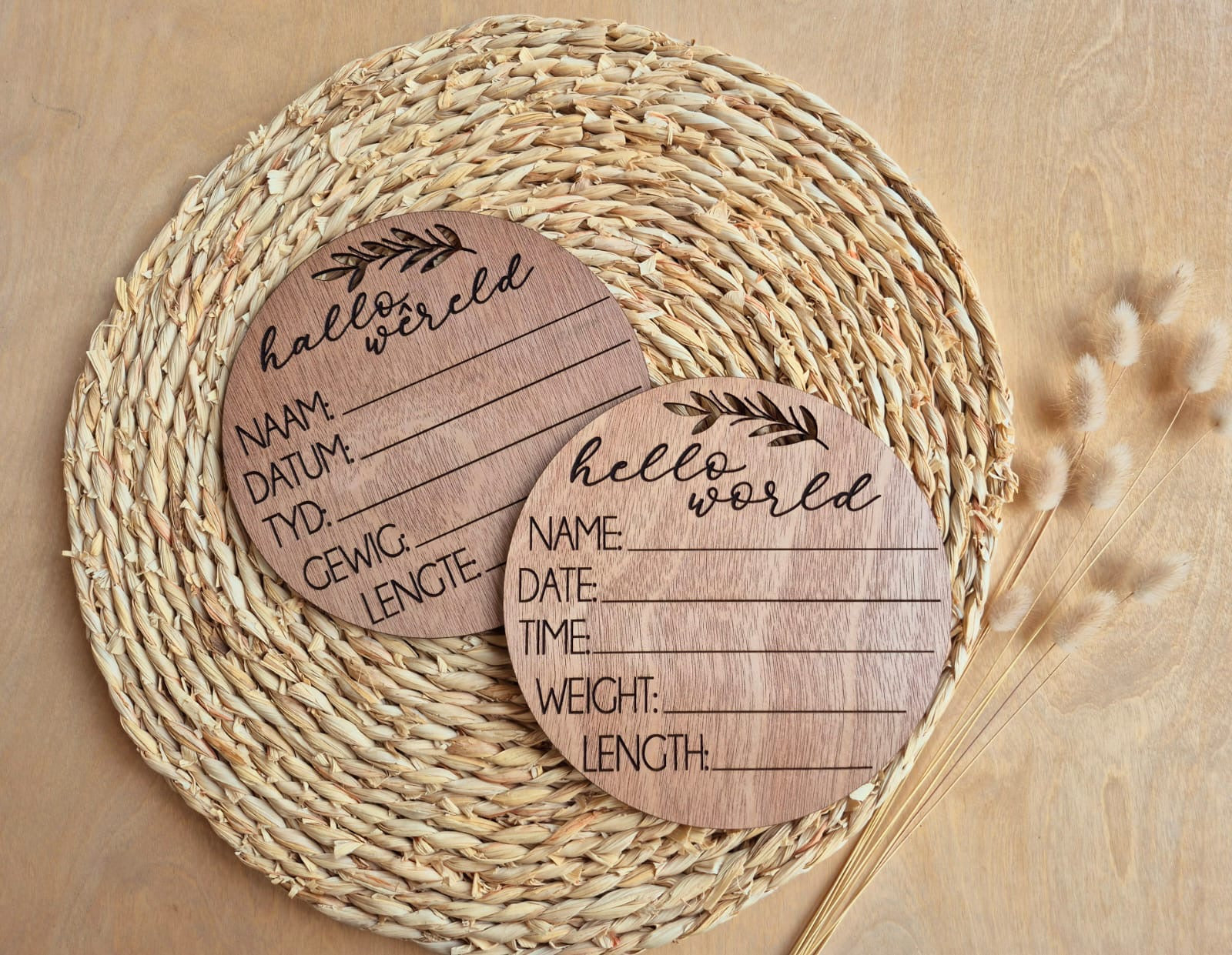 Two wooden baby announcement cards with text on a woven mat.