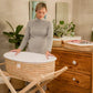 Woman holding a woven baby crib in a room with wooden furniture and plants. | Baby Essentials | All Baby Products | Soft Spot Kids | South Africa