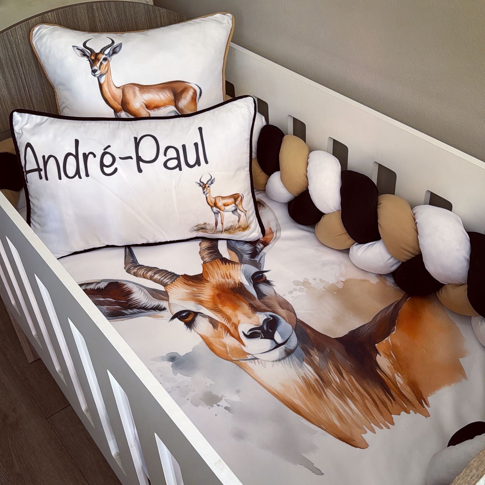 Crib with animal-themed bedding and pillows featuring a deer design.