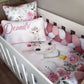 Crib with decorative bedding featuring a lamb and floral design, with 'Deandra' written on a pillow.
