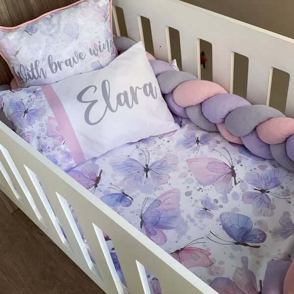 Crib with butterfly-themed bedding and decorative pillows.