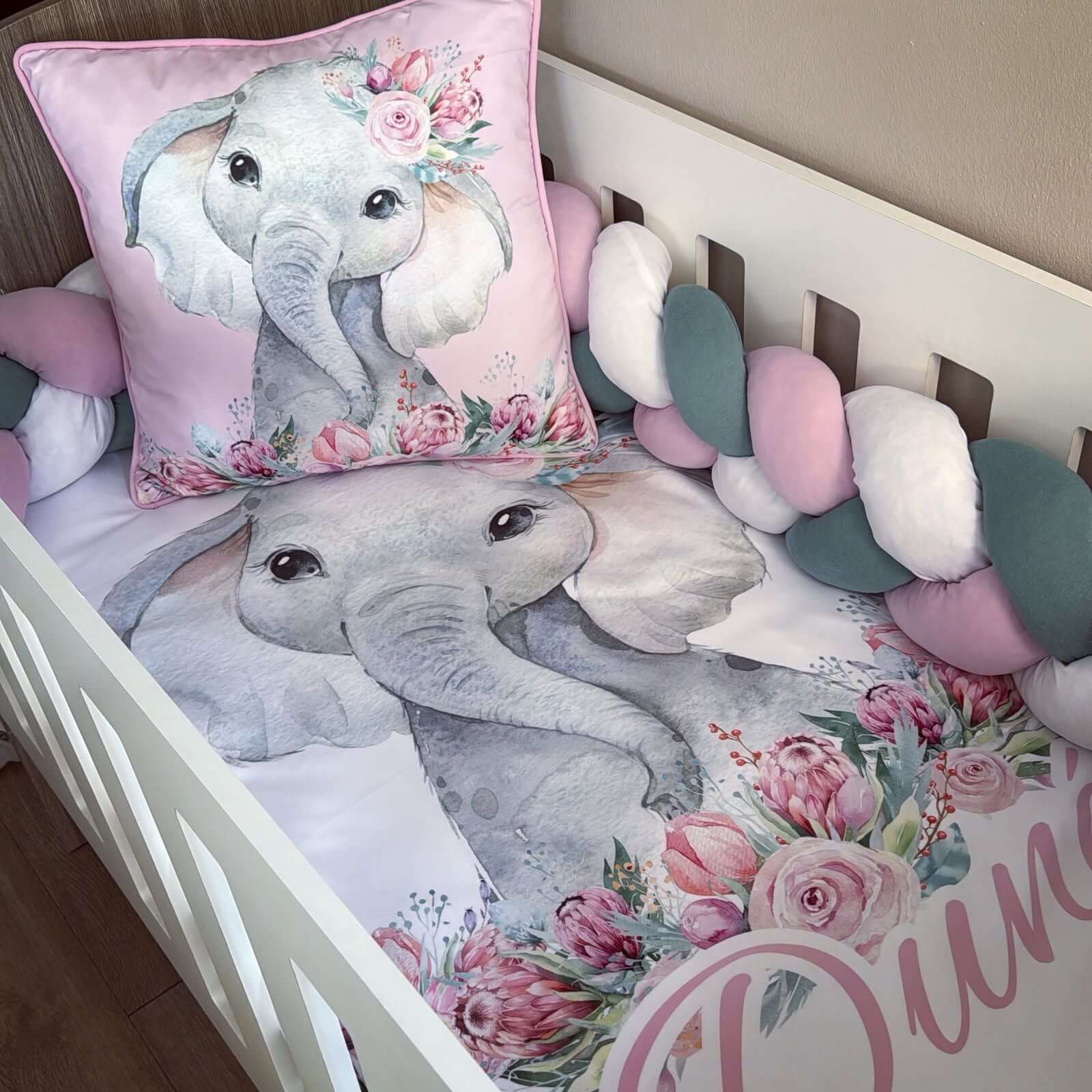 Crib with elephant-themed bedding and decorative pillows in a nursery setting.