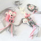 A set of four handmade felt animal charms with silver and pink ribbons, including a pink fox, white bunny, gray lion, and gray elephant, arranged on a white textured background. | Baby Essentials | All Baby Products | Soft Spot Kids | South Africa