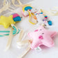 A set of handmade felt baby accessories including a pink star with embroidered eyes and mouth, a yellow star with pink and blue accents, a rainbow, and a unicorn, all attached to cream-colored ribbons on a white fabric background. | Baby Essentials | All Baby Products | Soft Spot Kids | South Africa