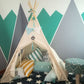 Children's teepee with pillows against a wall with geometric patterns